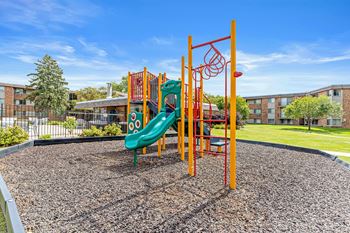 A playground with a green slide and orange climbing structure.
